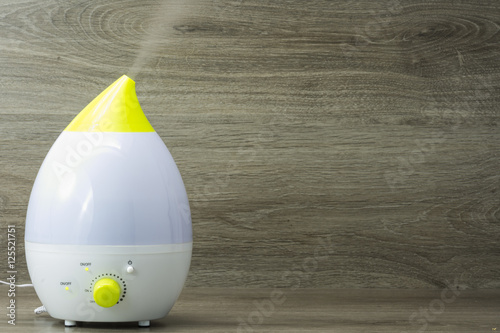 Poster humidificador de ultrasonidos funcionando sobre fondo de madera gris