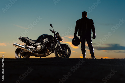 Silhouette of man in leather outfit with motorbike