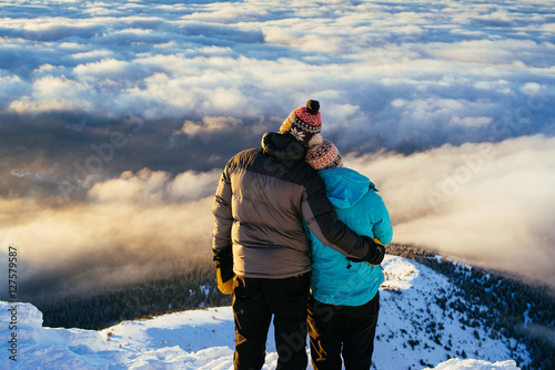 Loving couple stands on a top of the mountain and admire the inc