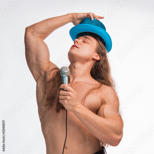 Poster singer bodybuilder shirtless with long hair in a blue hat with a microphone on a