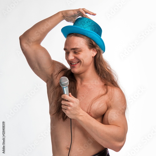 Poster singer bodybuilder shirtless with long hair in a blue hat with a microphone on a