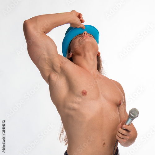Poster singer bodybuilder shirtless with long hair in a blue hat with a microphone on a