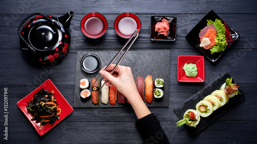 Woman eating sushi with chopsticks top view