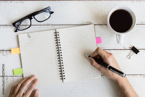 Cup of coffee with notebook and copy space on white wooden desk