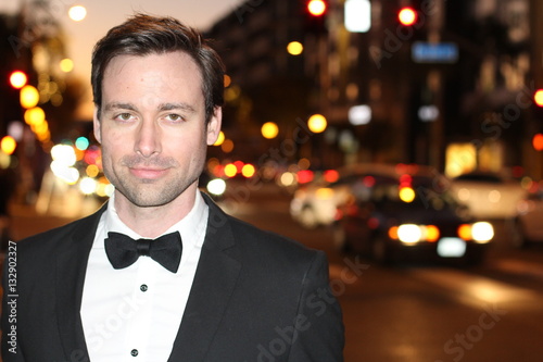 Poster Sexy man in tuxedo and bow tie posing in the city streets at night