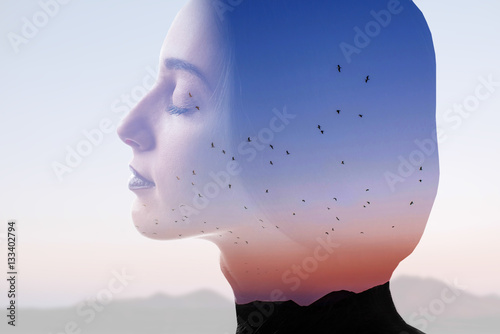 Double exposure photo with woman silhouette and sunset sky with mountains and birds. Freedom and travel concept