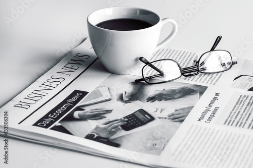 Newspaper with eyeglasses on white table