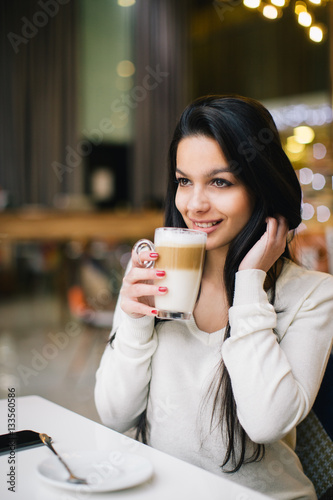 Young woman at cafe drinking coffee 