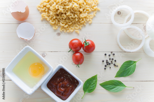 spaghetti with ingredients for cooking on wood background