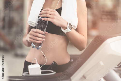 Slim woman holding a bottle after workout