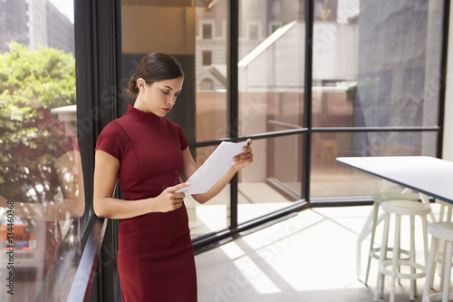 Young white businesswoman reading document in modern office