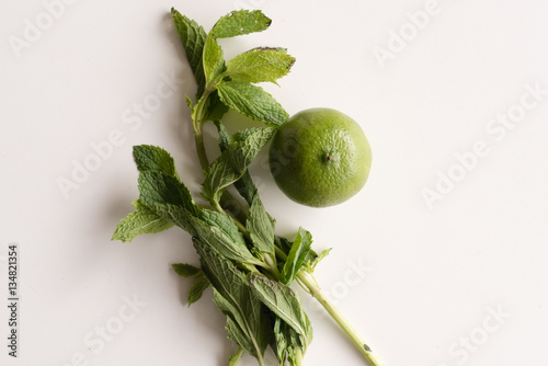 High angle view of natural looking green lime and mint on white table (selective focus)
