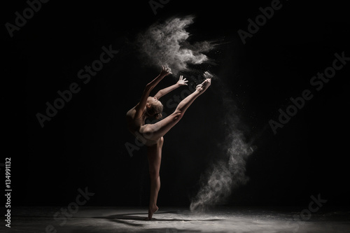 Obraz na płótnie Graceful girl dancing in cloud of dust studio shot