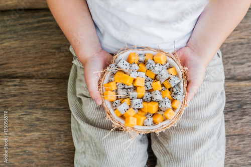 Poster Fruit salad with dragon fruit and papaya in half a coconut in hand