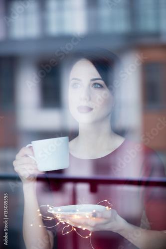 Beautiful redhead woman with cup of coffee or cappuccino near a