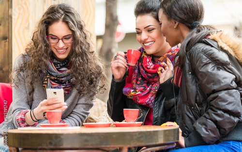 Women in cafe showing pictures on smart phone
