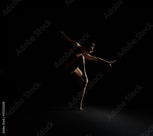 Obraz Fotograficzny Graceful girl dancing emotionally in dark studio