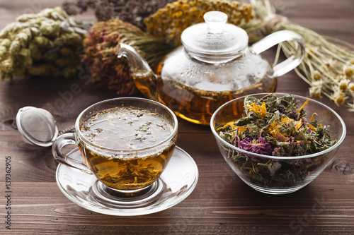 medicinal tea in glass cup with dried herb in bowl