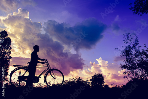Plakat foto vintage bicycle with biker man silhouette at sunset image
