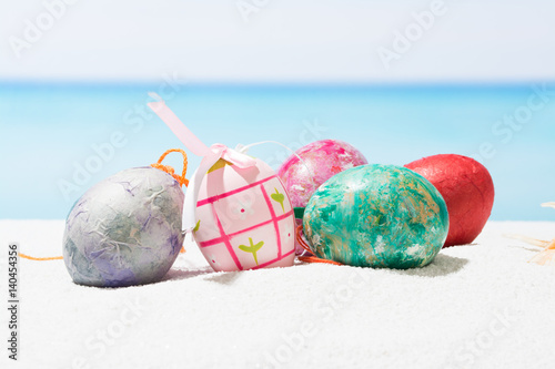 Easter on tropical beach background. Eggs on the white sand. Vacation and travel concept