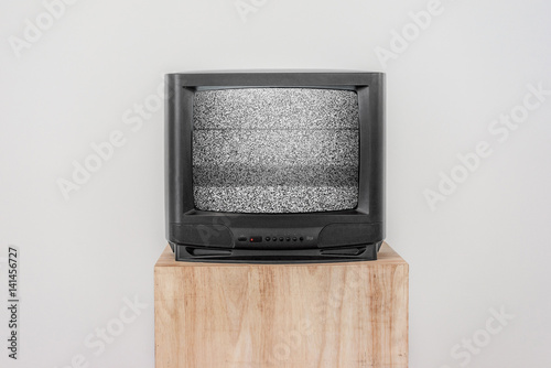Poster Old Black TV with screen noise on a wooden shelf, Isolated background