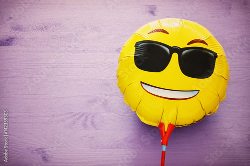 Poster image of cute smiling emoticon wearing black sunglasses, emoji concept