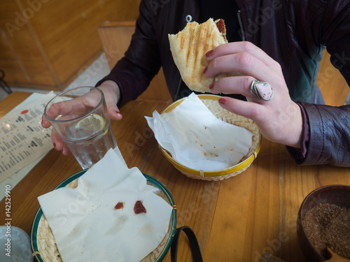 Poster Young woman eating a sandwich and drinking coffee in a coffee shop