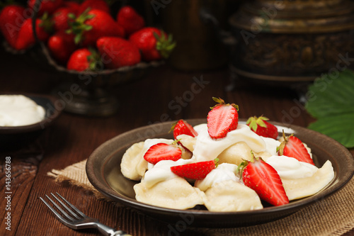 Delicious dumplings with fresh strawberries served with whipped cream and sugar.