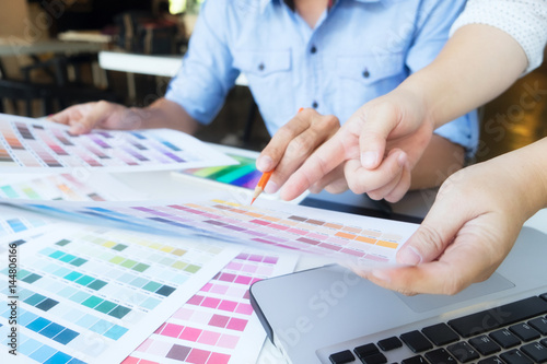 Poster Artist drawing on graphic tablet with color swatches in office.