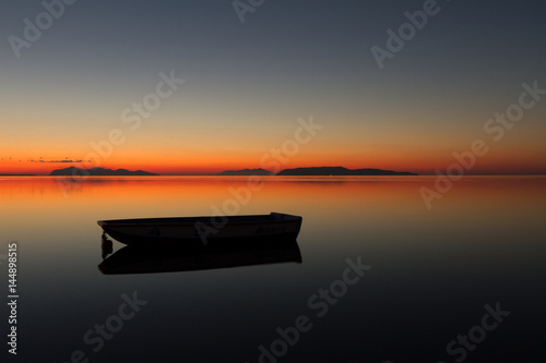 A warm sunset on a calm water, with Islands in the background