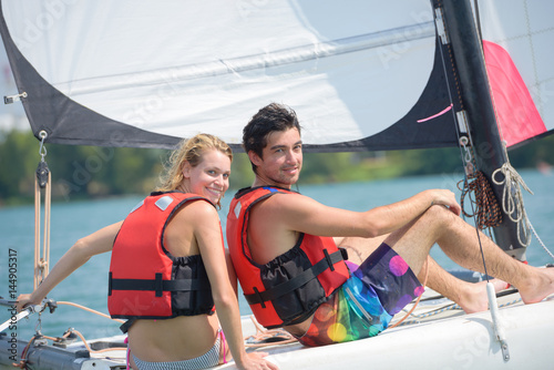 young couple steering a catamaran