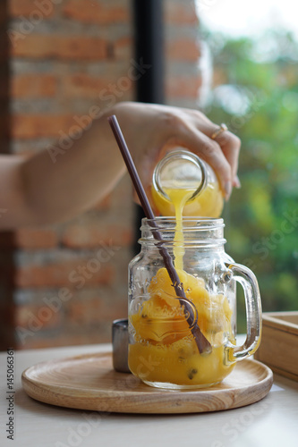 Woman pouring Passion fruit juice in the jar of passion fruit juice ice cube.