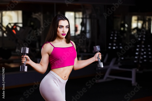 Poster Young attractive muscular fitness woman doing exercise for triceps with dumbbell
