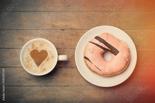 Poster photo of glazed donut and cup of coffee on the wonderful brown wooden background