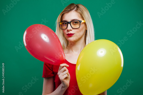 Poster Blonde Wearing Short Red Top and Glasses is Dancing with Two Air Balloons in Her Hands