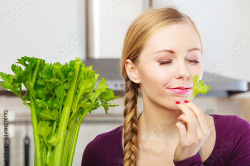 Woman in kitchen holds green celery