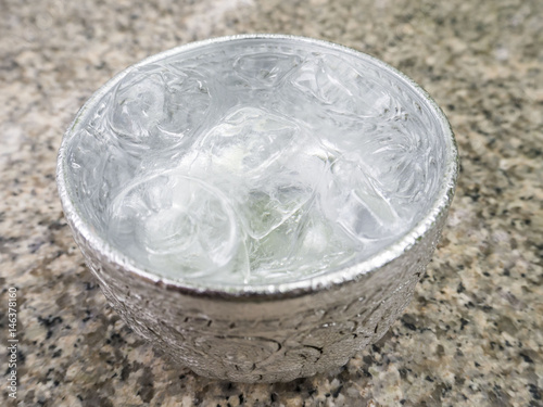 Aluminum bowl with water and  ice cube on the dining table in the restaurant, Thai style