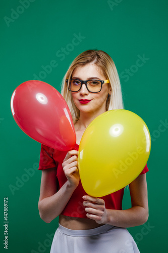 Poster Funny Joyous Girl Hides Behind the Red and Yellow Balloons, then Suddenly Appears and Smiles Widely Looking in the Camera