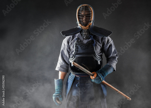 kendo-maestro-de-pie-en-armadura-tradicional-el-sostiene-la-espada-de-bambu-shinai