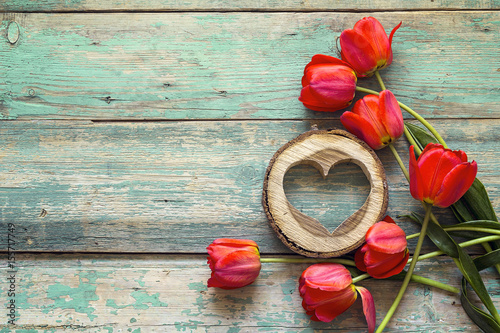 Background with red tulips and wooden hearts on old wooden boards.