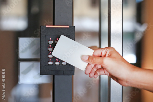 Door access control - young woman holding a key card to lock and unlock door.