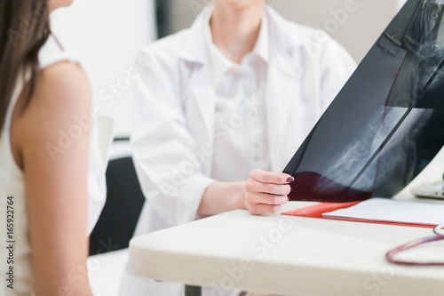 Female doctor holding the Mammogram film image and give advice her patient in consulting room.