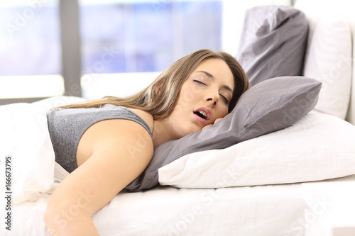 Tired woman resting on a bed at home