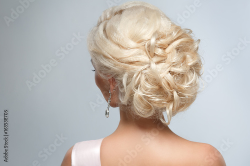 A smart wedding hairstyle on a blonde woman on a gray background. © ksi