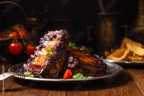 Obraz na płótnie Roasted ribs, served on an old plate. Dark or balck background.