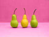 Pears Pop art Two green and one yellow pears are standing upright in a row on pink background Trendy still life with fruits