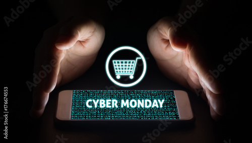 Man hands holding smart phone with cyber monday text and cart on virtual screens on smartphone.