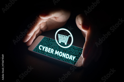 Man hands holding smart phone with cyber monday text and cart on virtual screens on smartphone.