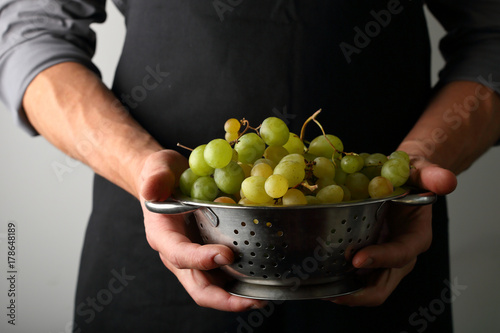 Harvest of grapes in colander in hands
