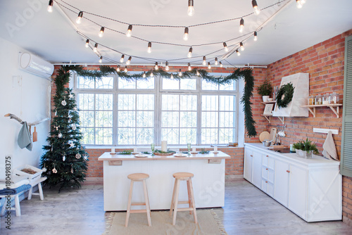 New Year and Christmas 2018. Festive kitchen in Christmas decorations. Candles, spruce branches, wooden stands, table laying.